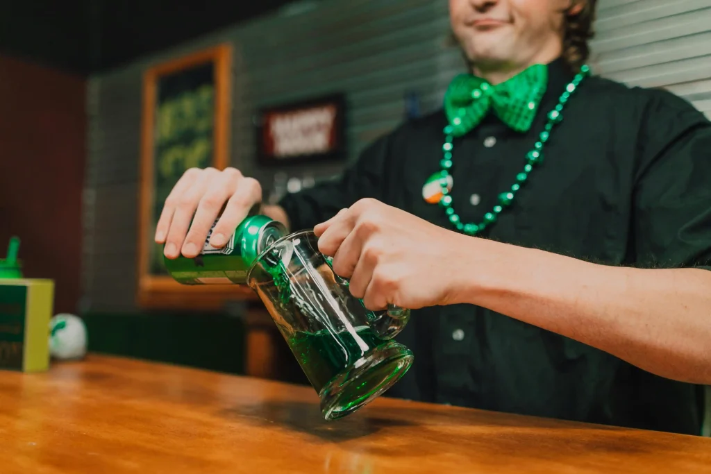 A bartender pouring a green beverage into a mug, showcasing the role of bartenders as key jobs in hospitality.