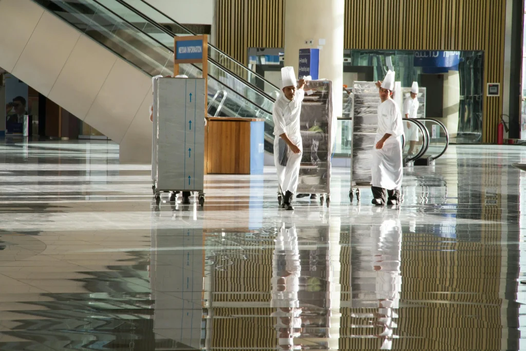 Chefs transporting food trolleys in a large venue, showcasing teamwork and organization as key skills needed for hospitality.