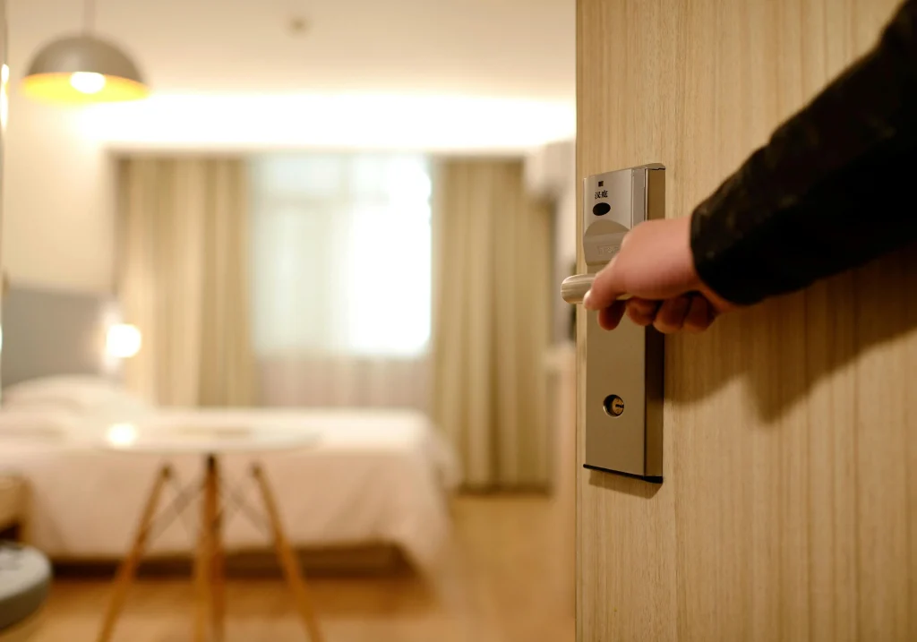 A hospitality trainee opening a hotel room door, symbolizing career opportunities from hospitality training programs in London.
