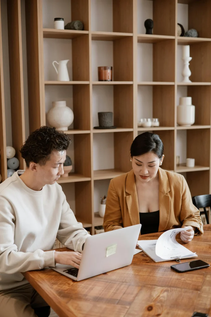 Two individuals engaged in a discussion about Zero-Hour Contract Rules, collaborating on documents in a cozy office setting with shelves in the background.